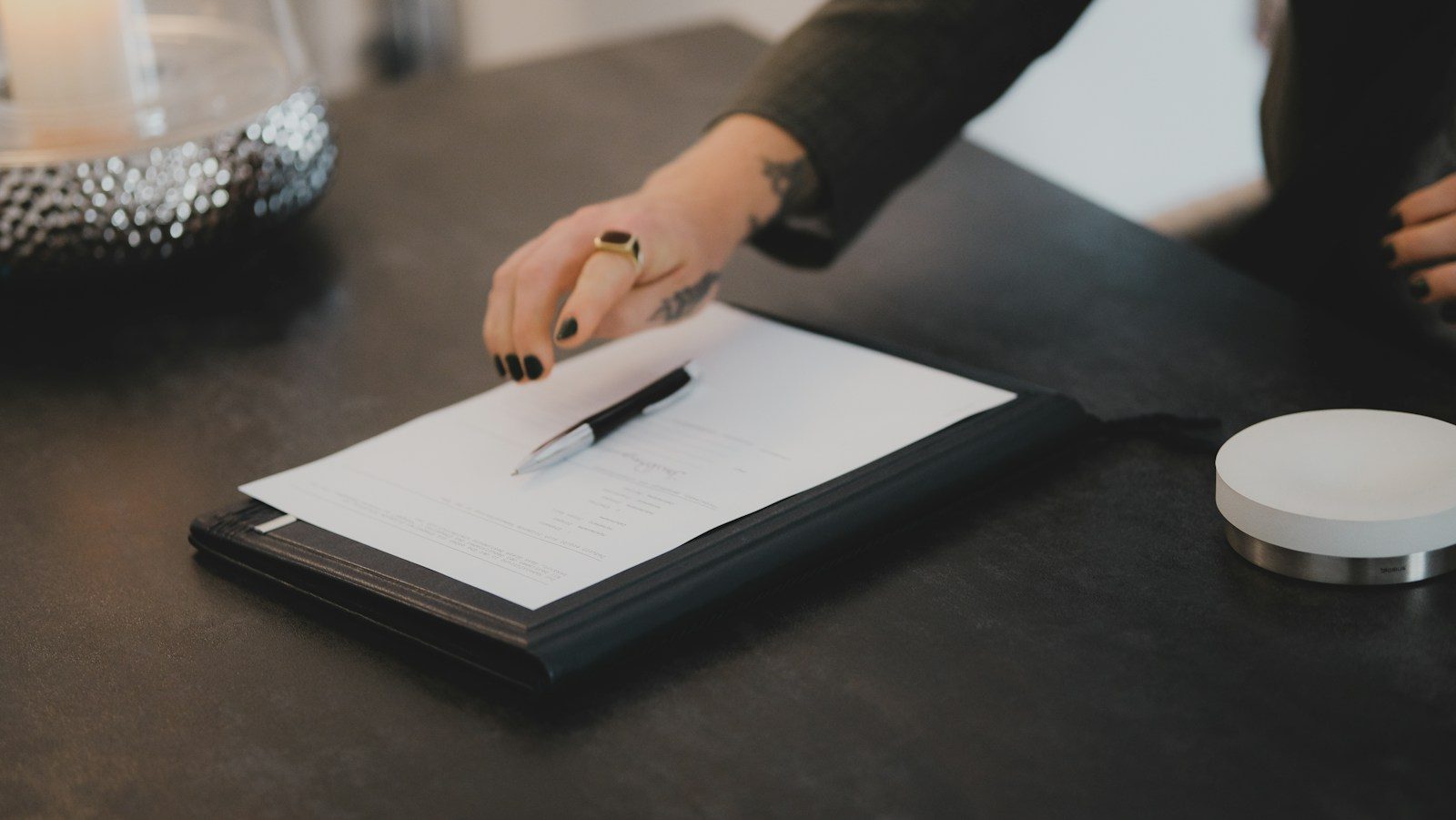 Hand die een pen neerlegt op een klembord met een blad papier